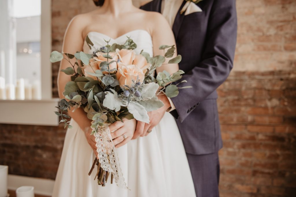 un couple de marié qui ce font un calin et qui tienne un bouquet de fleur